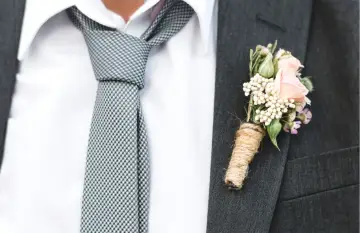 Elegancki krawat do ślubu w kratkę, biała koszula i butonierka z różową różą.