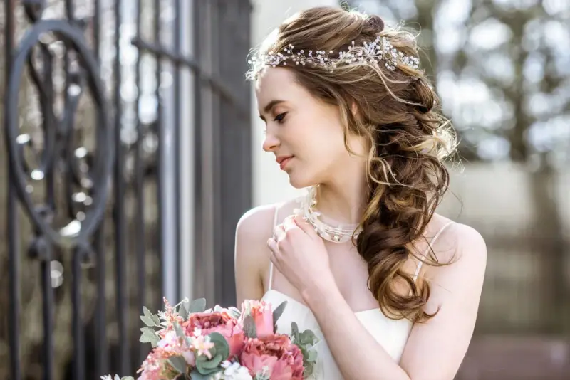 Upięta fryzura glamour z ozdobami z pereł i kryształków, delikatny bukiet róż i piwonii.